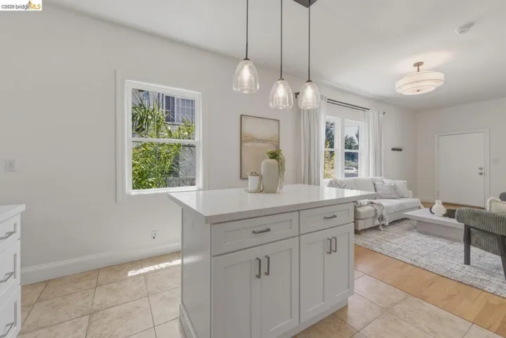 Kitchen island with white shaker cabinetry, an integrated white countertop, and three pendant light fixtures