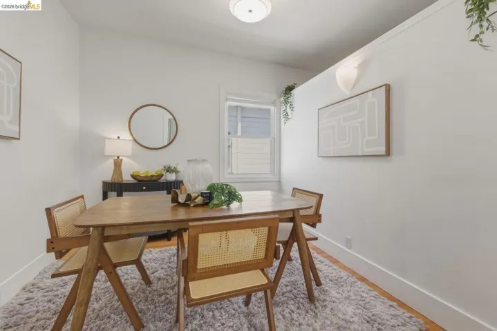 Dining area featuring wood-finish flooring, white baseboards, a single window, and a ceiling-mounted light fixture
