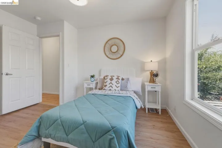 Bedroom featuring wood-finish flooring, a double-hung window, and a white paneled door