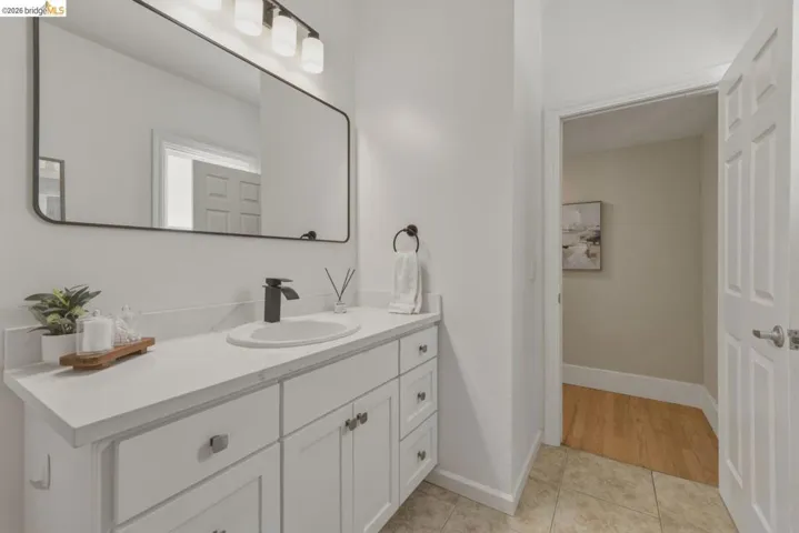 White vanity with a white countertop and oval undermount sink, accented by a matte black faucet