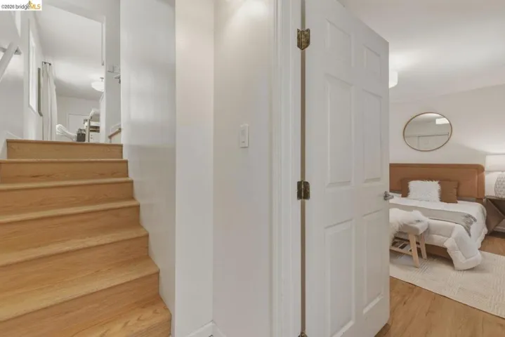 Wood-finish stair treads with white risers ascend to an upper level