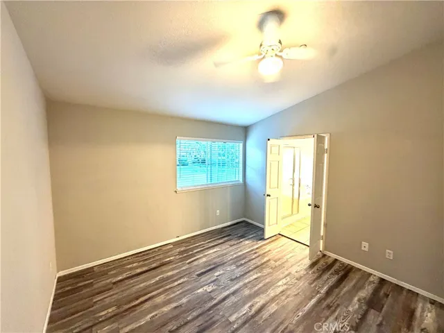 Primary bedroom view into primary bath. Ceiling fan & one window facing backside.