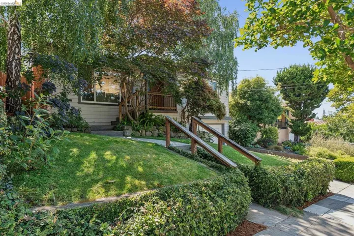 Front exterior featuring mature trees, sloped lawn, and established shrubbery