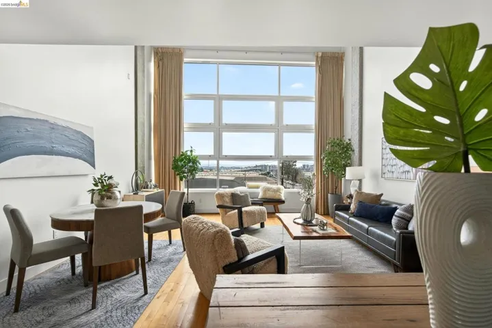 Spacious living area featuring large paneled windows, wood-finish flooring, a light gray area rug, and neutral wall tones