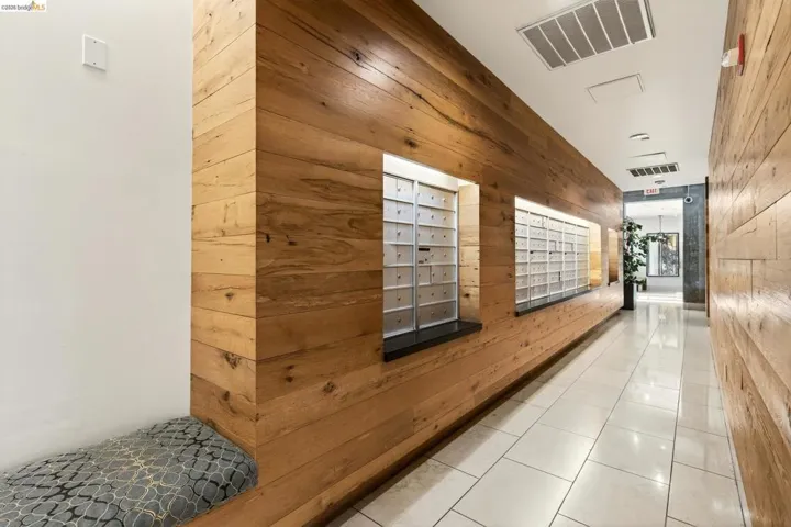 Hallway featuring extensive wood-paneled walls, white floor tiling, and recessed lighting