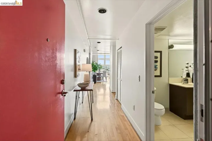 Entryway featuring a red door, wood-finish flooring, recessed lighting, and a bathroom with tile flooring and a vanity with a surface-mount sink