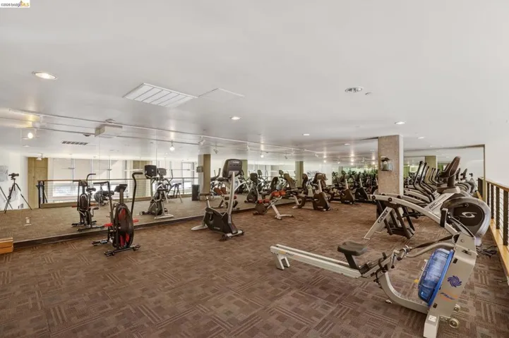Fitness center featuring mirrored walls, recessed lighting, patterned carpet flooring, and a variety of exercise equipment