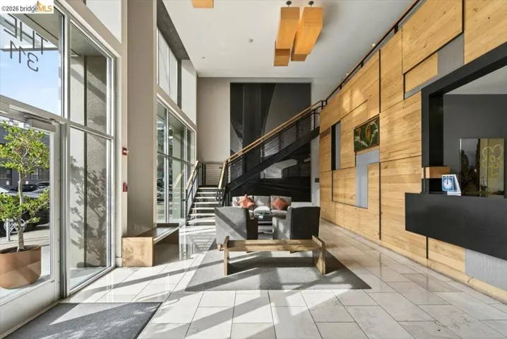 Lobby with a wood-paneled feature wall, white tile flooring, and a contemporary black metal staircase with cable railings
