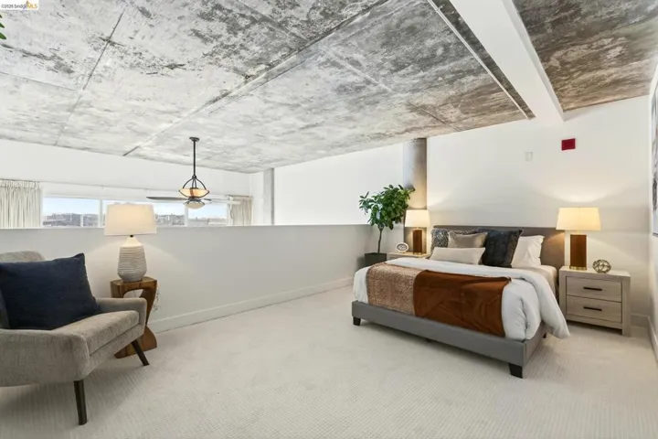Expansive room featuring a concrete ceiling, light-colored carpeting, a partial-height wall, and a ceiling fan with integrated lighting