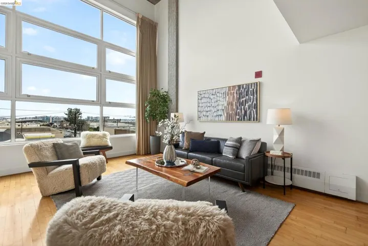 Expansive living area with a full wall of multi-pane windows, wood-finish flooring, and a high vaulted ceiling