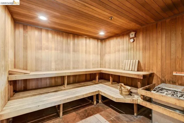 Wood-paneled sauna featuring tiered wooden benches and an integrated heater