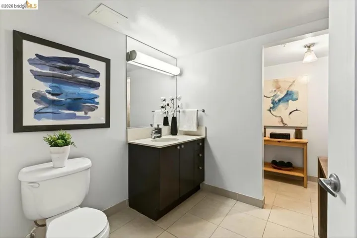 Contemporary bathroom featuring a dark wood-finish vanity with an integrated sink, full-width mirror, and overhead linear lighting
