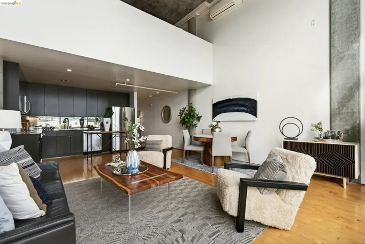 Open-concept living space featuring high ceilings, wood-finish flooring, a modern kitchen with dark cabinetry, and a dining area
