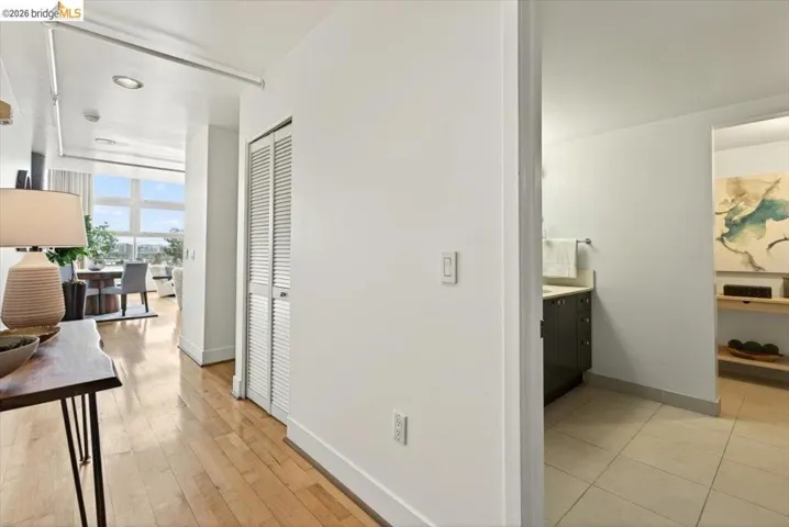 Hardwood-finish flooring extending into the main living space, a full-lite door opening to a bathroom with tile flooring and a vanity, and a louvered bi-fold door