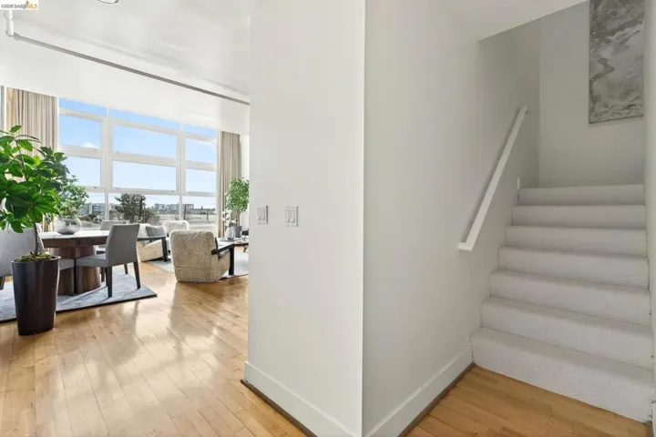 Hardwood flooring extends from the entryway into the open-concept living space, featuring a dining area with a modern chandelier