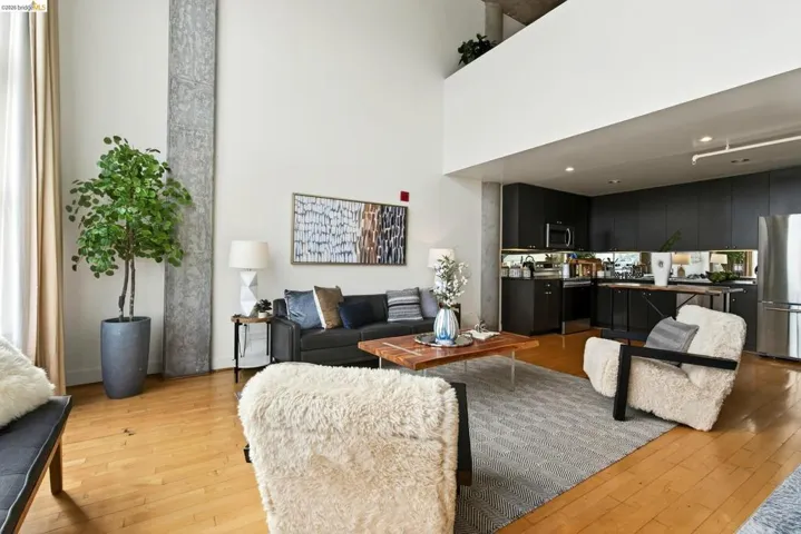 Open concept living area featuring high ceilings, wood-finish flooring, and exposed concrete architectural elements