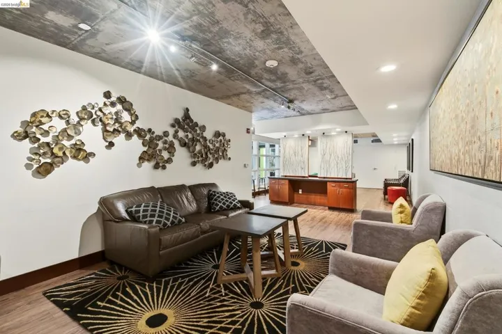 Lounge area featuring concrete ceiling, track lighting, wood-finish flooring, and a built-in wood-finish reception desk