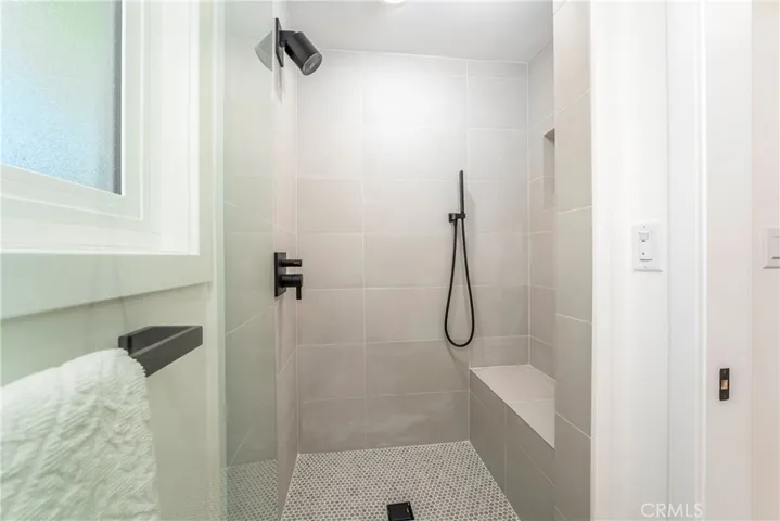 Primary bath with dual sink vanity, medicine cabinet, lighted mirror, pocket door to shower with bench & shower wand, plus separate showerhead & shampoo niche. Electrical receptacle for bidet.