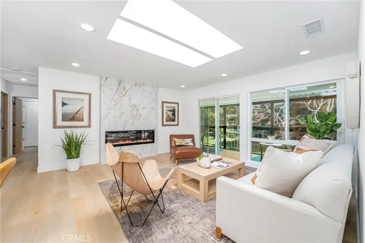Luxurious and comfortable living room with recessed lighting, skylight, electric fireplace with TV outlet, large storage closet and wonderful patio overlooking the greenbelt