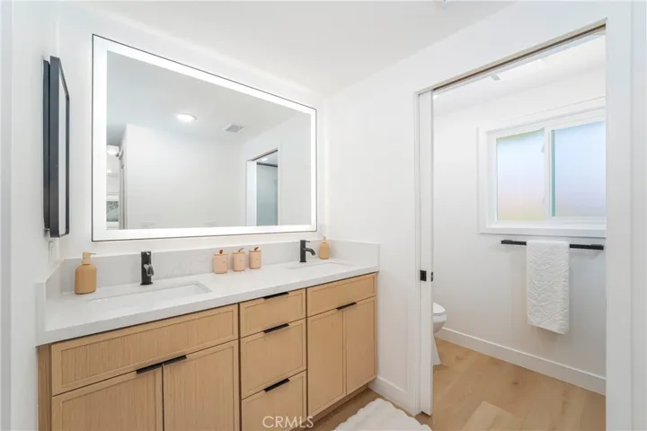 Primary bath with dual sink vanity, medicine cabinet, lighted mirror, pocket door to shower with bench & shower wand, plus separate showerhead & shampoo niche. Electrical receptacle for bidet.