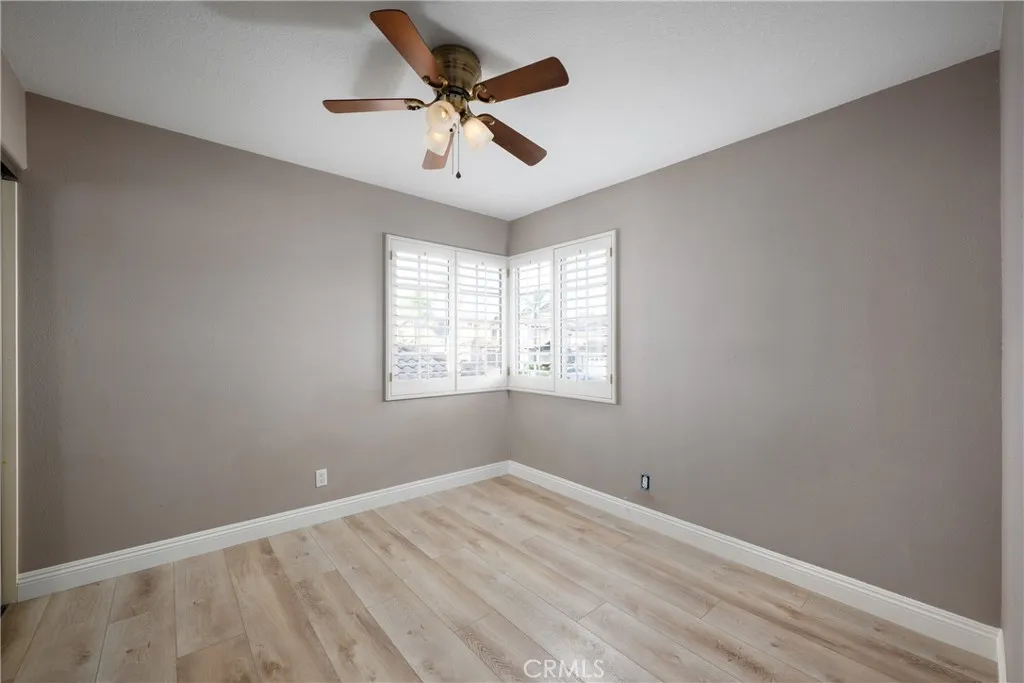 Additional guest bedroom located upstairs with a ceiling fan and plantation shutters.