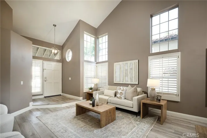 The living room features a soaring vaulted ceiling and plantation shutters.