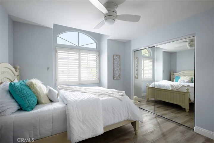 Guest bedroom located upstairs with a ceiling fan and plantation shutters.