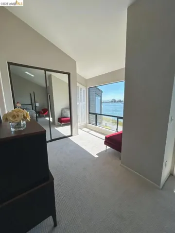 Waterfront room featuring a large picture window, light-colored carpeting, and a mirrored closet