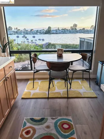 Expansive window offering water frontage, a waterside patio, and distant homes