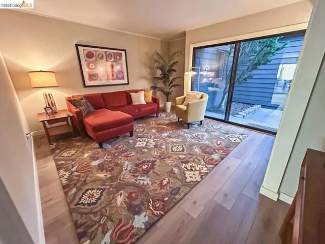 Open concept room featuring wood-finish flooring, a large area rug, and a sliding glass door
