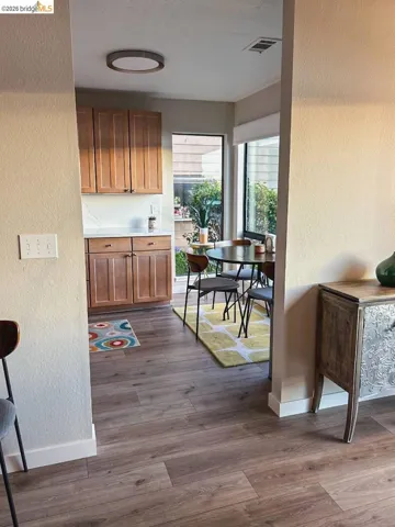 Open kitchen and dining area featuring wood-finish flooring, wood cabinetry, and a modern ceiling light fixture