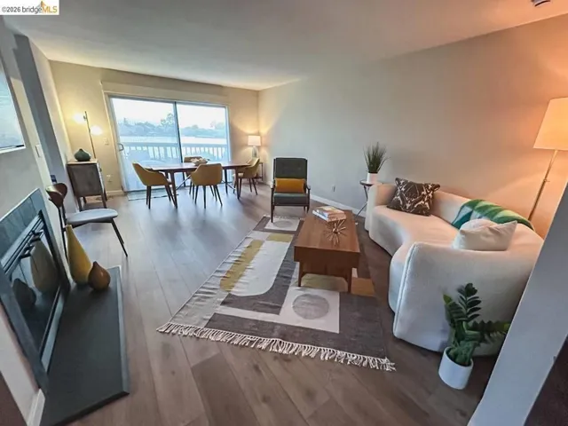 Living area featuring wood-finish flooring, a fireplace with a dark mantel, and a sliding glass door
