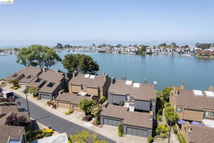 Waterfront residential community featuring brown shingle roofs, integrated garages, mature landscaping, and private boat slips