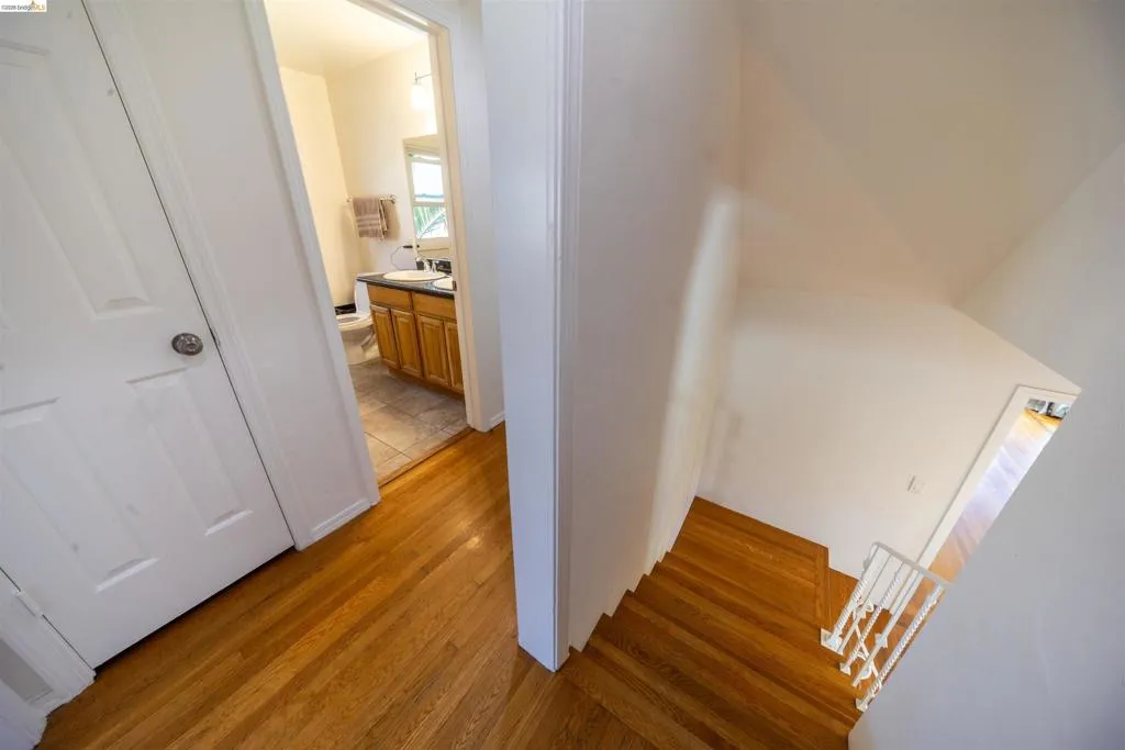 Hardwood flooring throughout the hallway and staircase, featuring a white painted handrail