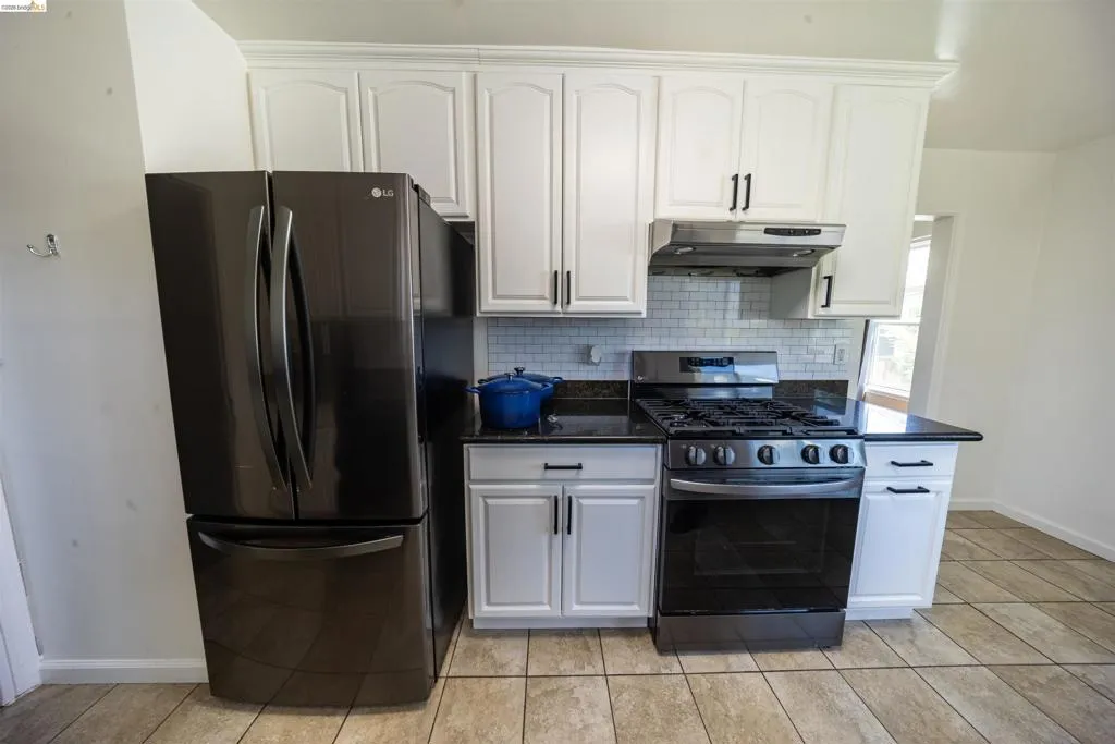 Kitchen featuring white shaker-style cabinetry, black countertops, and a white subway tile backsplash