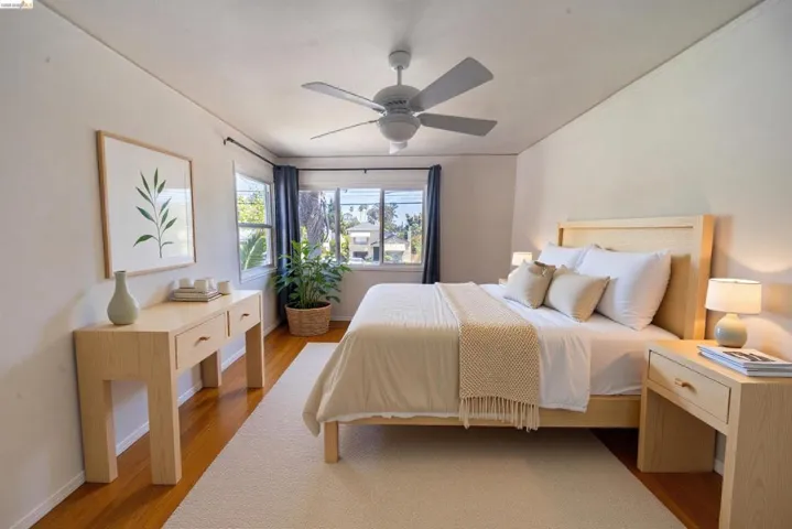 Well-lit sleeping area featuring wood-finish flooring and a ceiling fan with integrated lighting