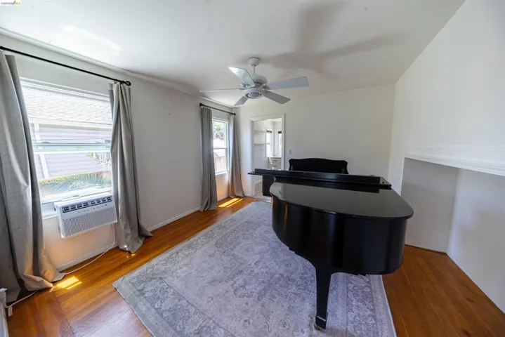 Room featuring wood-finish flooring, white walls, and two windows with drapery