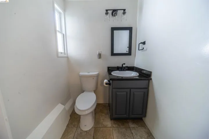 Bathroom featuring a dark gray vanity with a dark countertop, an undermount sink, and a framed mirror