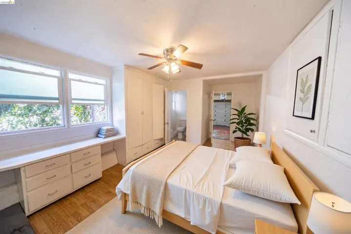 Bedroom featuring wood-finish flooring, multiple windows, a built-in desk with drawers, and a built-in wardrobe