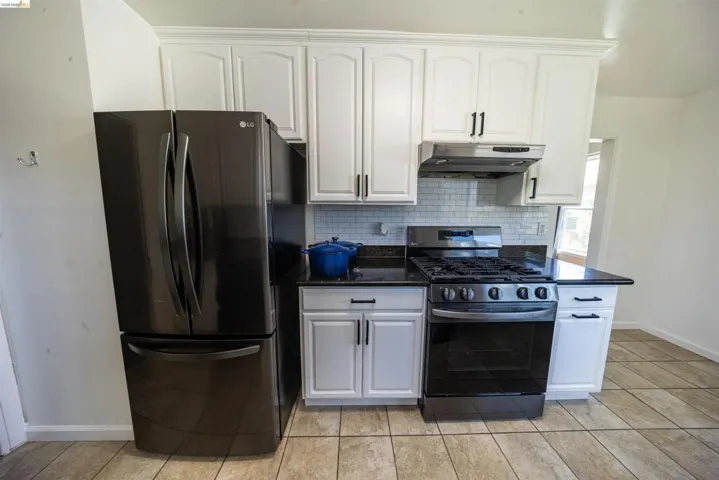 Kitchen featuring white shaker-style cabinetry, black countertops, and a white subway tile backsplash