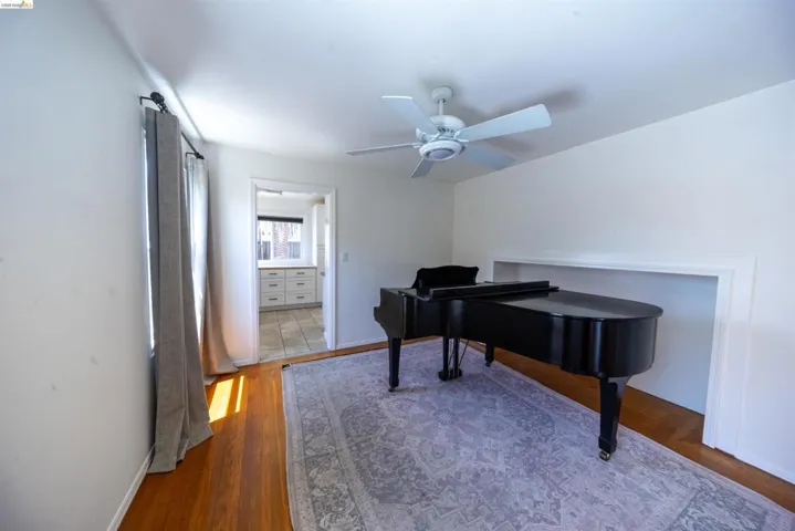 Bright room with wood-finish flooring, a ceiling fan, and a built-in wall niche