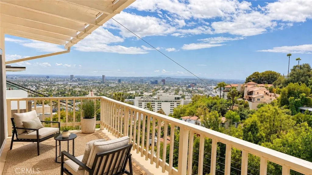 Balcony/Deck — Virtually staged to show possible outdoor seating arrangement. Furniture, plants, rug, and accessories are not included. Original unstaged photo shown adjacent.