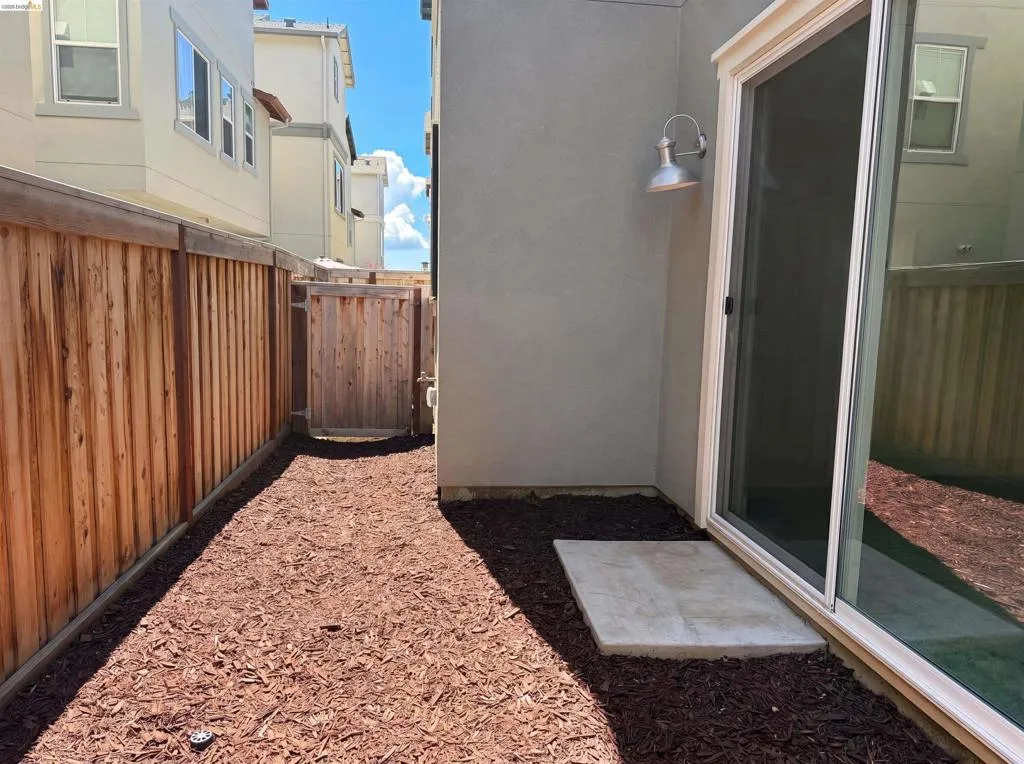 Private outdoor space featuring wood chip ground cover and a wood privacy fence