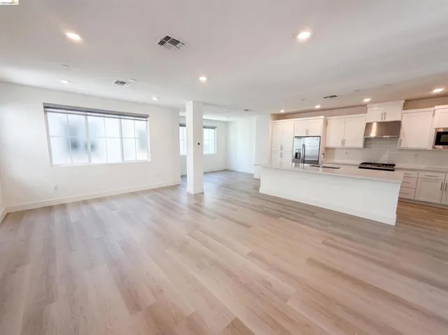 Open-concept living space featuring wood-finish flooring, recessed lighting, and large windows