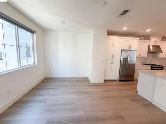 Open-concept living space featuring wood-finish flooring, recessed lighting, and a window with a roller shade