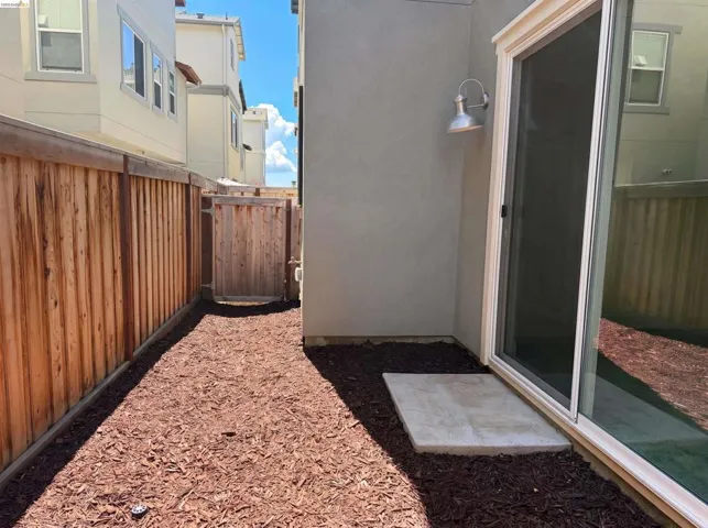 Private outdoor space featuring wood chip ground cover and a wood privacy fence