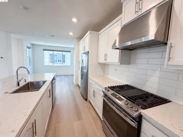 Modern kitchen featuring wood-finish flooring and white cabinetry with brushed nickel hardware
