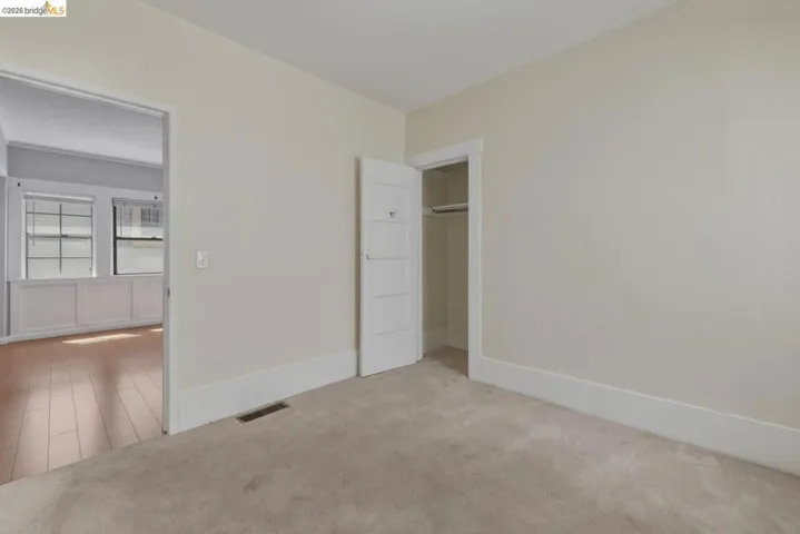 Carpeted room featuring a built-in closet with a white five-panel door, light-colored walls, and white baseboards