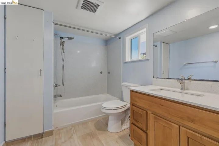 Bathroom featuring a full vanity with wood-finish cabinetry, a white countertop, and a large wall-mounted mirror