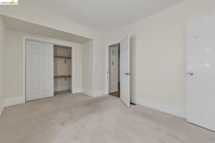 Carpeted room with a sliding two-panel closet door revealing interior shelving and a clothing rod